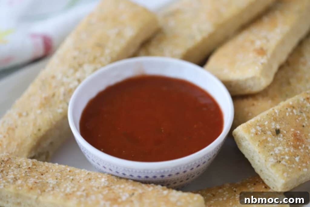 Golden Grain Breadsticks 5 Freshly baked homemade breadsticks with a bowl of marinara sauce for dipping.