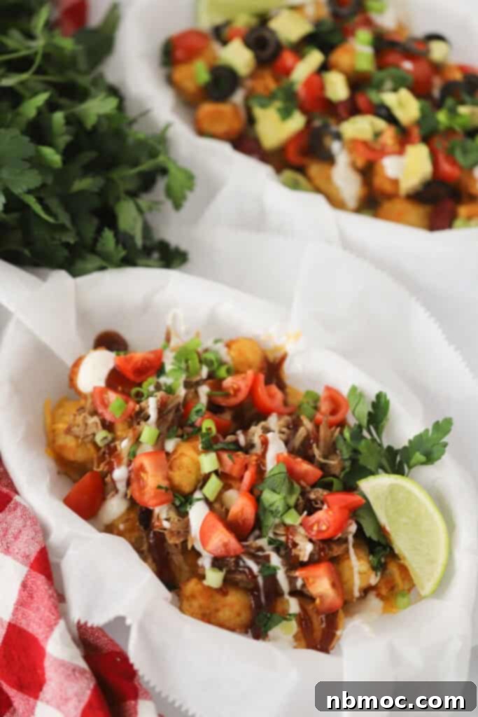 A parchment paper lined basket full of totchos made from baking tater tots with pork, cheese, and sauces and then topping with tomatoes, green onions, and cilantro.