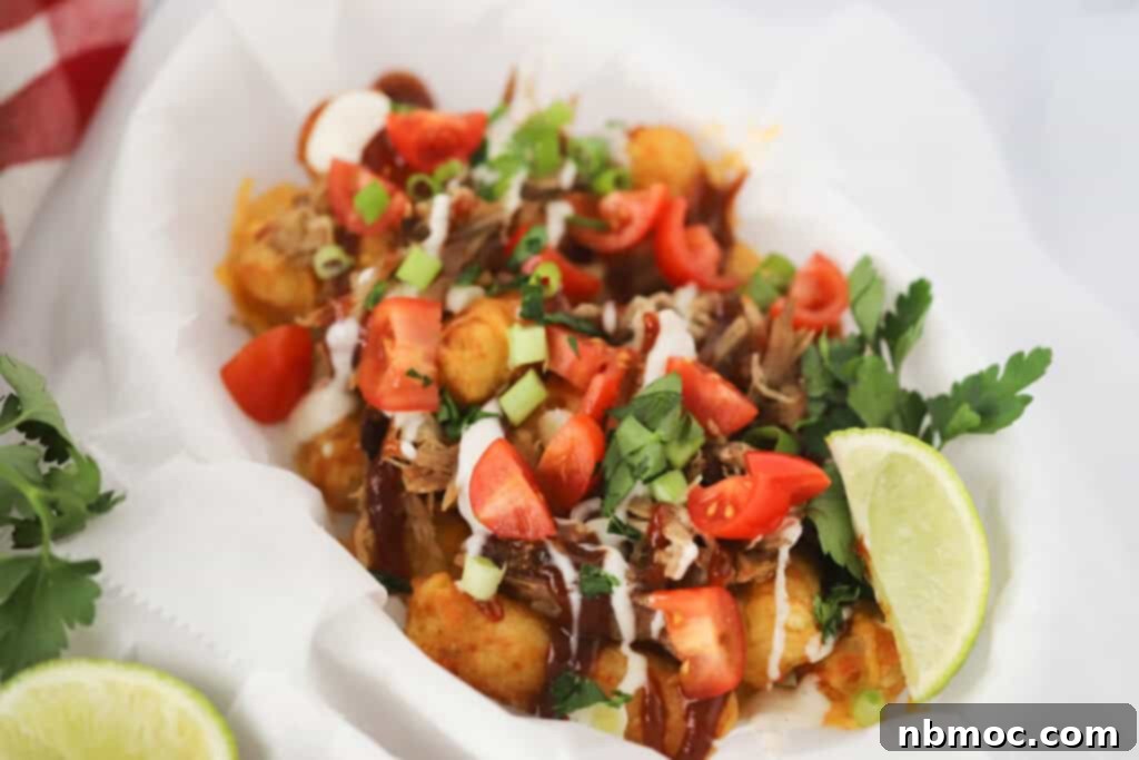 Loaded tater tot nachos in a basket with shredded pork, ranch dressing, and other nachos toppings.