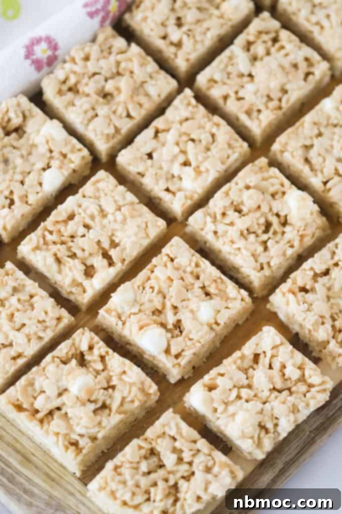 Caramel Rice Krispie Treats cut and lined up on a cutting board, showcasing their golden hue and inviting texture.