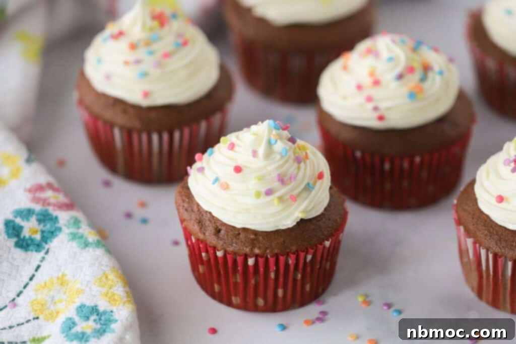 Chocolate cupcakes on a table with white chocolate cream cheese frosting piped on top.