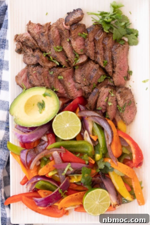 Sizzling Steak Fajitas 5 Steak fajitas sliced on a white plate along with veggies, avocado and lime, easy beef fajita recipe. marinade for fajita steak, fajitas marinade steak, beef fajita marinade recipe.