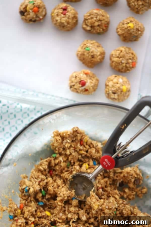 Peanut Coconut Fuel Bites 2 A large mixing bowl full of peanut butter and oats mixture with a cookie scoop scooping out peanut butter protein balls.