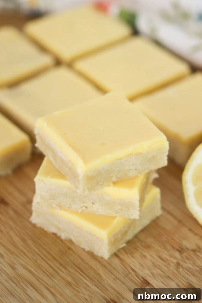 Homemade lemon blondies cut into squares and topped with lemon icing, arranged on a rustic wooden board.