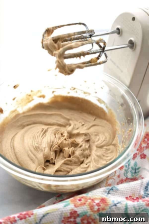 A glistening glass bowl filled with freshly whipped honey butter, speckled with cinnamon.