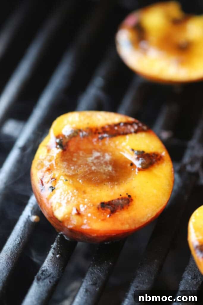 Fire Kissed Peaches 2 Grilled peaches cooking on a grill with a butter and brown sugar glaze melting over the top.
