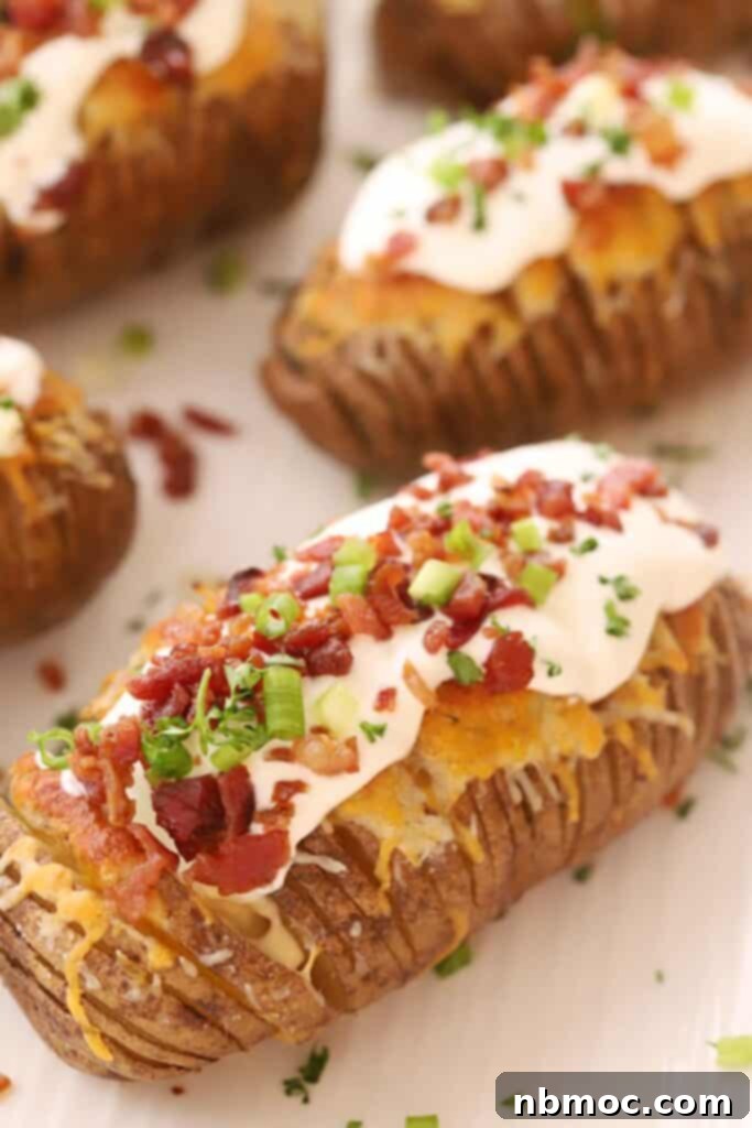 Crispy & Tender Hasselback Potatoes Made Easy 2 Fully loaded hasselback potatoes with cheese and bacon, topped with sour cream, bacon bits, sliced green onions, and plenty of cheese.