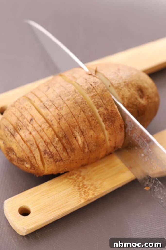 Crispy & Tender Hasselback Potatoes Made Easy 3 A knife thinly slicing through a potato using two wood spoons as guides
