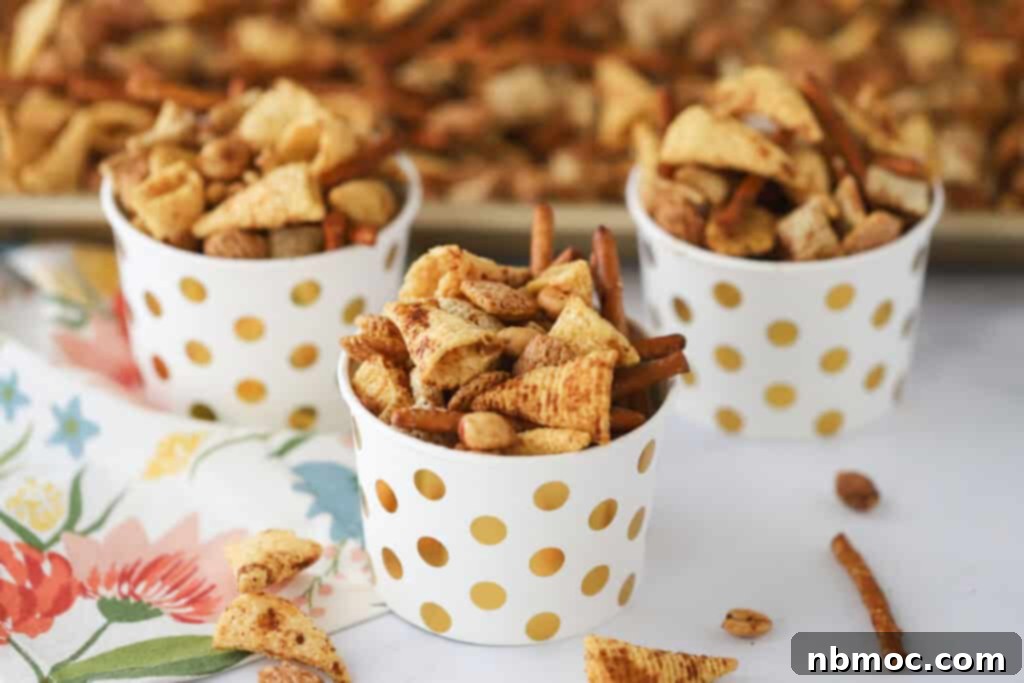 Individual serving cups filled with crunchy homemade Chex Mix, featuring a delicious assortment of Bugles, pretzels, and roasted peanuts.