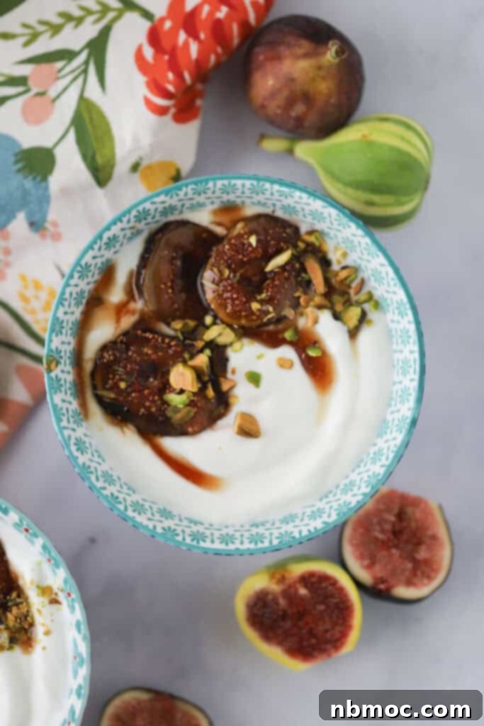 A small bowl of creamy Greek yogurt generously topped with warm, caramelized figs, a drizzle of thyme-infused honey, and crunchy pistachios.