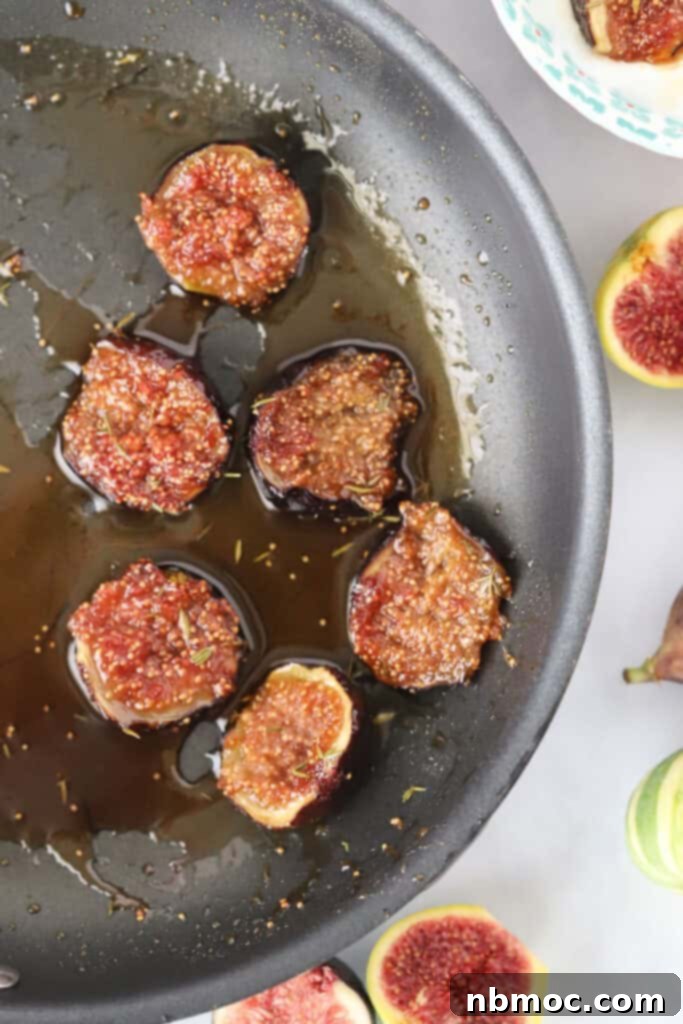 A saute pan with halved figs being caramelized in a bubbling mixture of honey and fresh thyme.