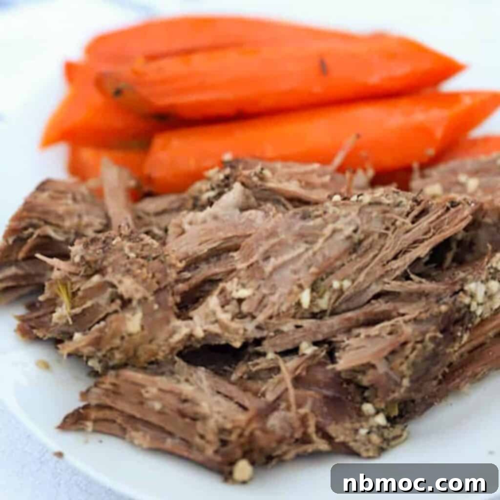 Tender slow cooker venison roast served on a plate with cooked carrots and gravy.