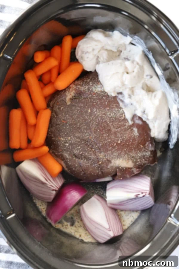 Venison and hearty vegetables simmering in a crockpot, creating a savory aroma for the slow cooker venison roast.