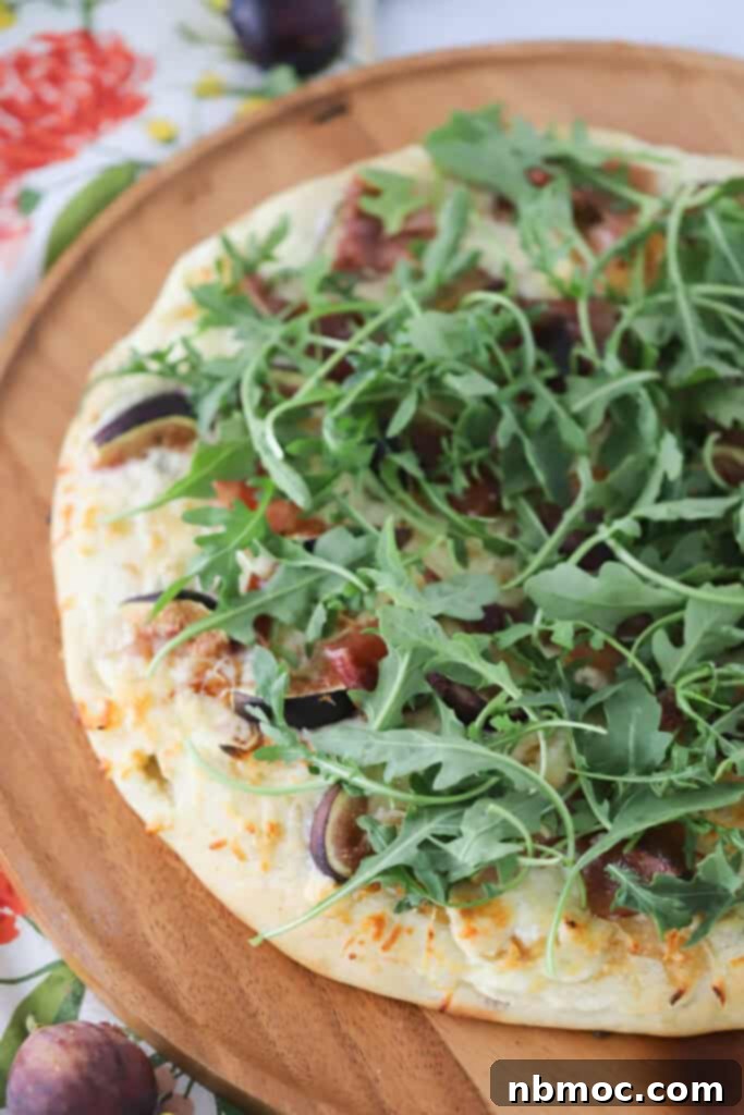 A full homemade pizza topped with figs, prosciutto, and fresh arugula.