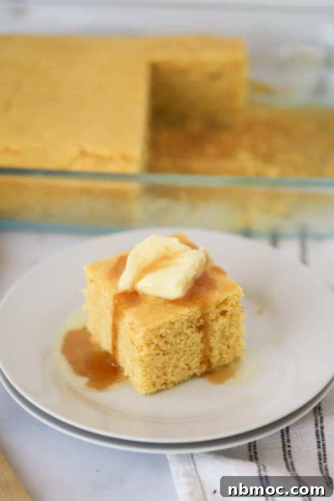 Easy homemade cornbread recipe topped with butter and syrup on a white plate.