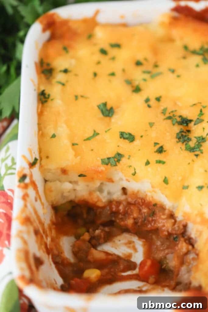 A casserole dish full of golden-brown shepherd's pie with ground beef and mashed potatoes, ready to serve.
