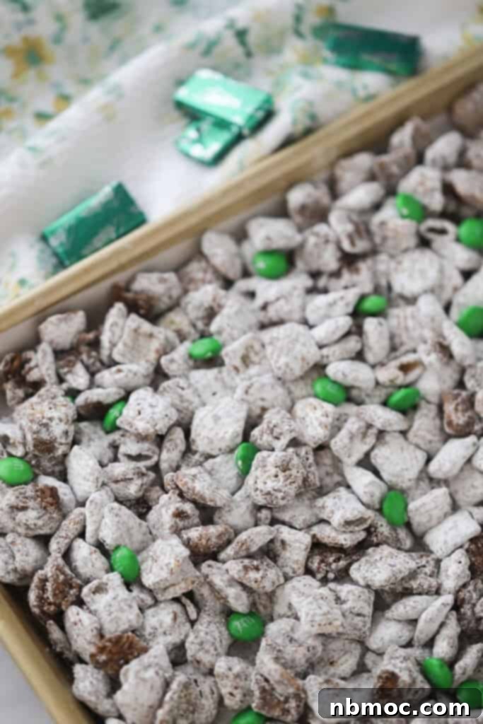 Crisp Mint Chocolate Snack Mix 4 A large container filled with mint puppy chow and scattered green M&Ms.