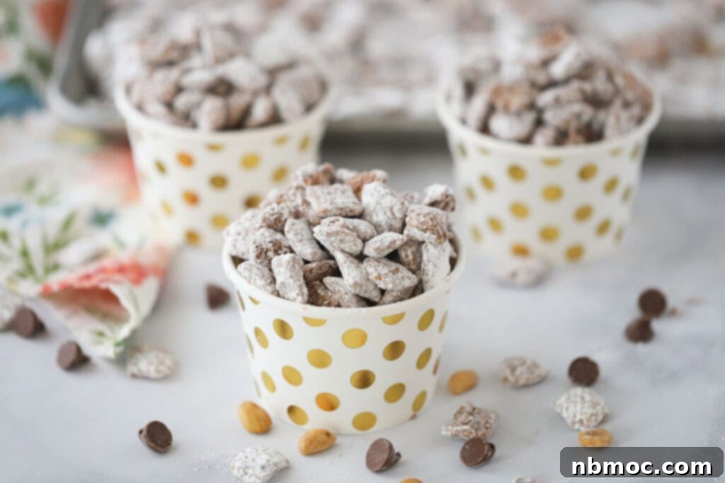 Small decorative cups filled with puppy chow that is covered in powdered sugar, ready for serving.