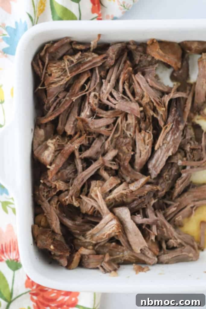Chuck roast in a baking dish to be used for French Dip sandwiches, ready for the slow cooker.
