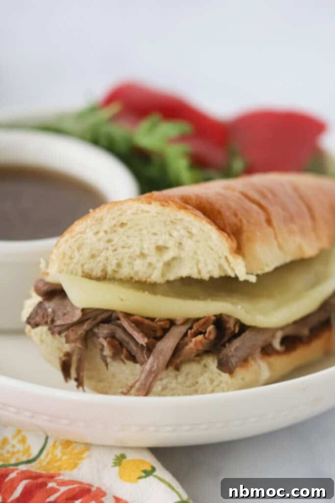 A serving plate with a French Dip Sandwich that is made with slow cooked beef and cheese, ready for dipping.