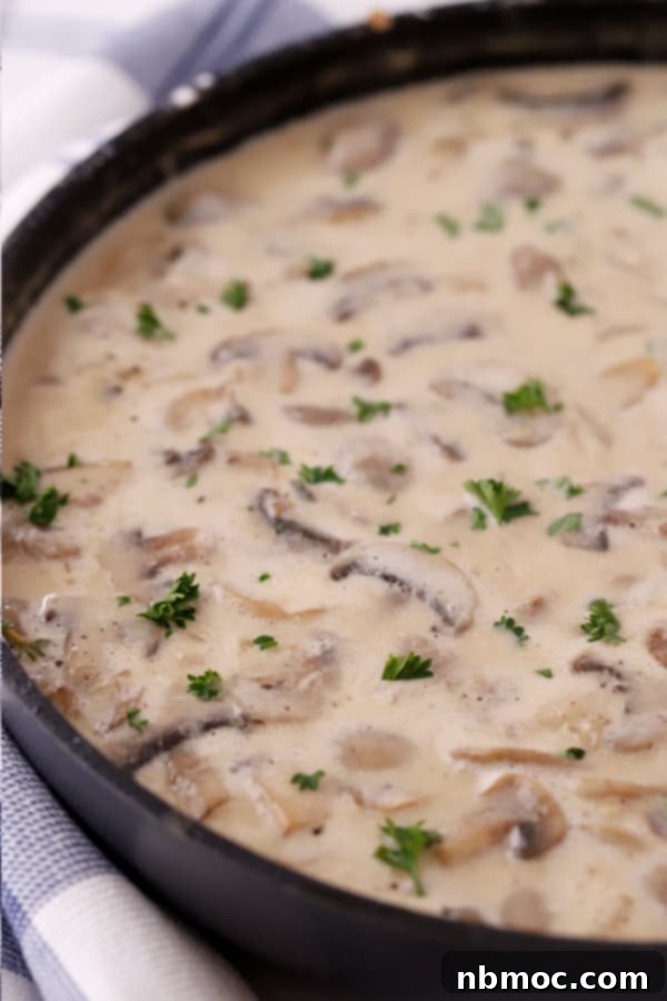 Creamy sour cream sauce for this traditional stroganoff recipe simmering in a pan.