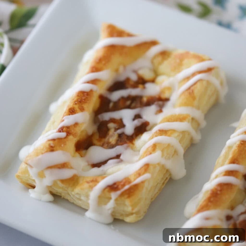 A beautifully arranged serving platter showcasing freshly baked pumpkin danish, each generously topped with a delicate vanilla glaze, ready to be enjoyed.