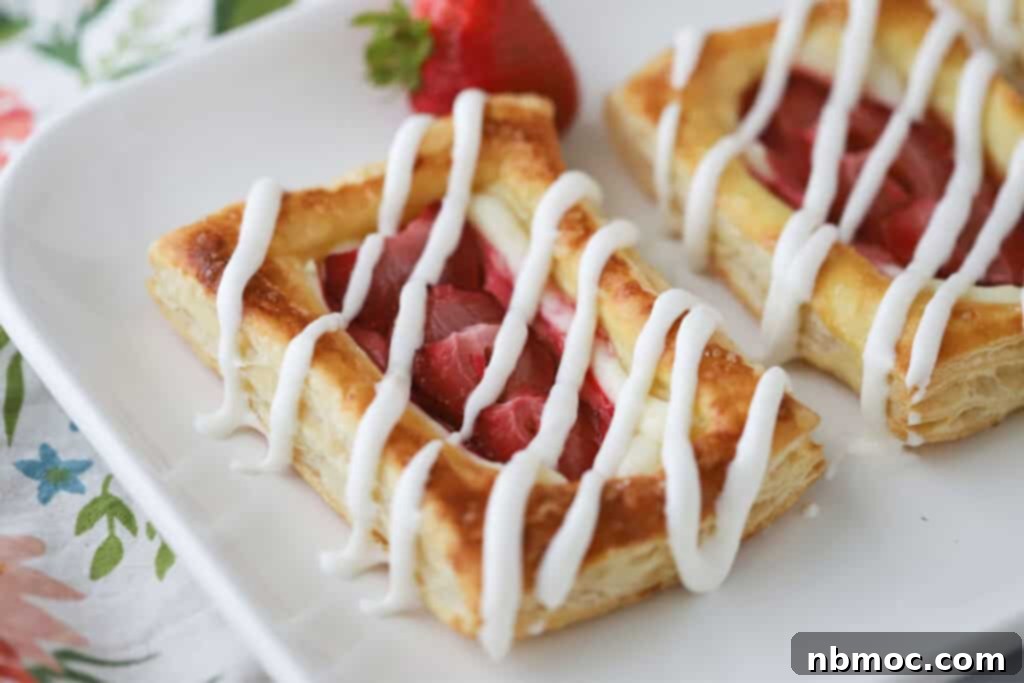 Flaky Strawberry Cream Cheese Delight 5 A white plate full of strawberry danish made with puff pastry.