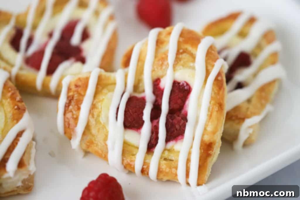 A serving plate full of raspberry Danishes made with puff pastry and fresh raspberries, beautifully glazed and ready to eat.