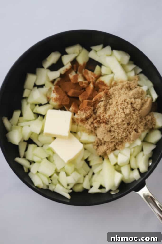 A saute pan filled with diced apples, brown sugar, cinnamon, and melted butter, cooking to create a delicious apple danish filling.