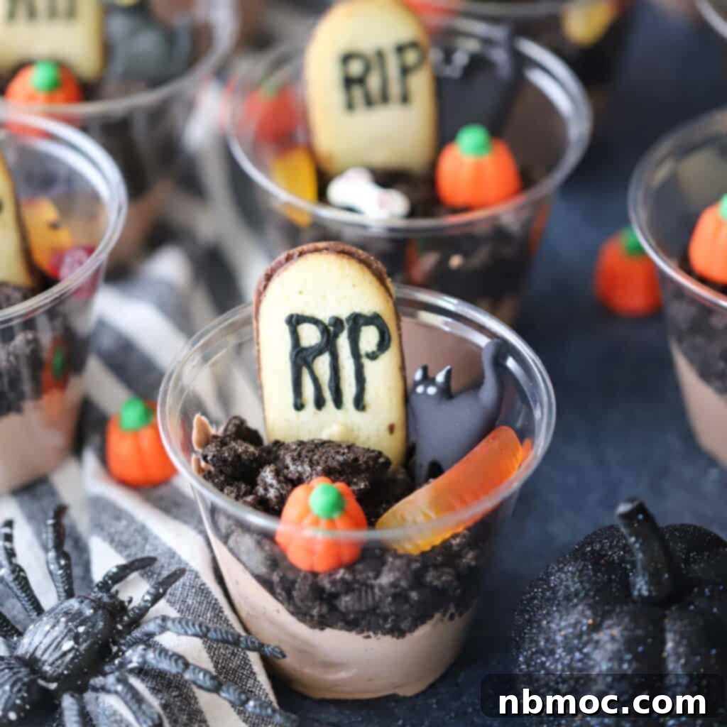 A collection of graveyard dirt cups, artfully decorated for a Halloween party with crushed Oreos, gummy worms, and candy tombstones, creating an edible spooky scene.