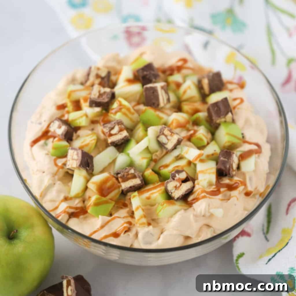 A generous bowl brimming with Snickers apple salad, a tempting blend of sweet and tart flavors.