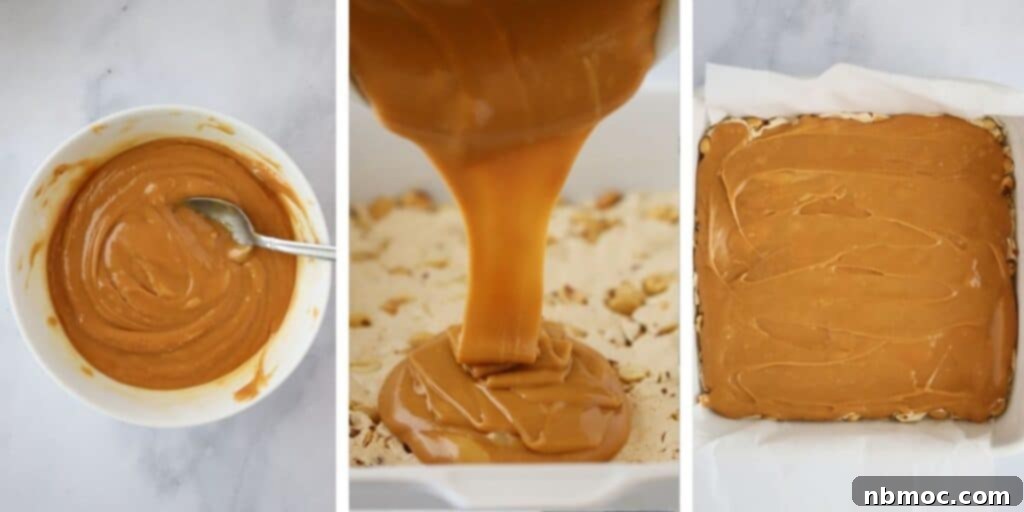 Pouring melted caramels over the top of a nougat layer to make homemade Snickers bars.