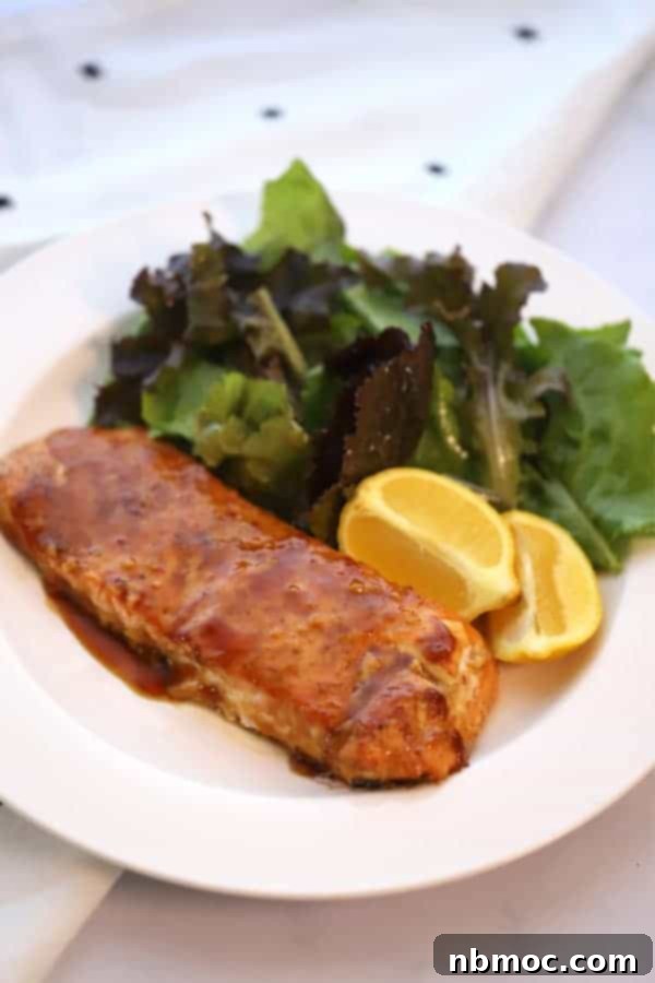 Sticky Teriyaki Salmon Grill 5 A beautifully presented white serving plate with a portion of glazed teriyaki salmon, fresh lemon wedges, and a vibrant side salad. A complete cedar plank salmon meal.