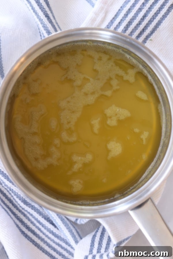 A small pot contains a golden fruit glaze, ready to be drizzled over fruit salad, showcasing the easy fruit glaze recipe process.