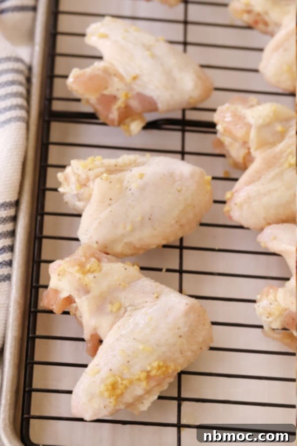 Simple Oven Buffalo Wings 3 Raw chicken covered in garlic on a wire rack ready to bake. baked wings recipe, chicken wing recipes, how long do you bake chicken wings, wings in oven, chicken wings recipe oven.
