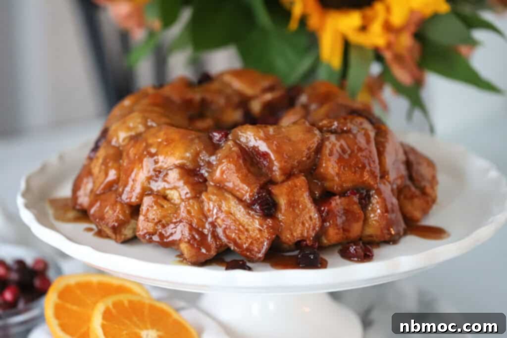 Zesty Cranberry Orange Pull-Apart Delight 7 A serving platter on a table with a full monkey bread covered with caramel sauce and cranberries.