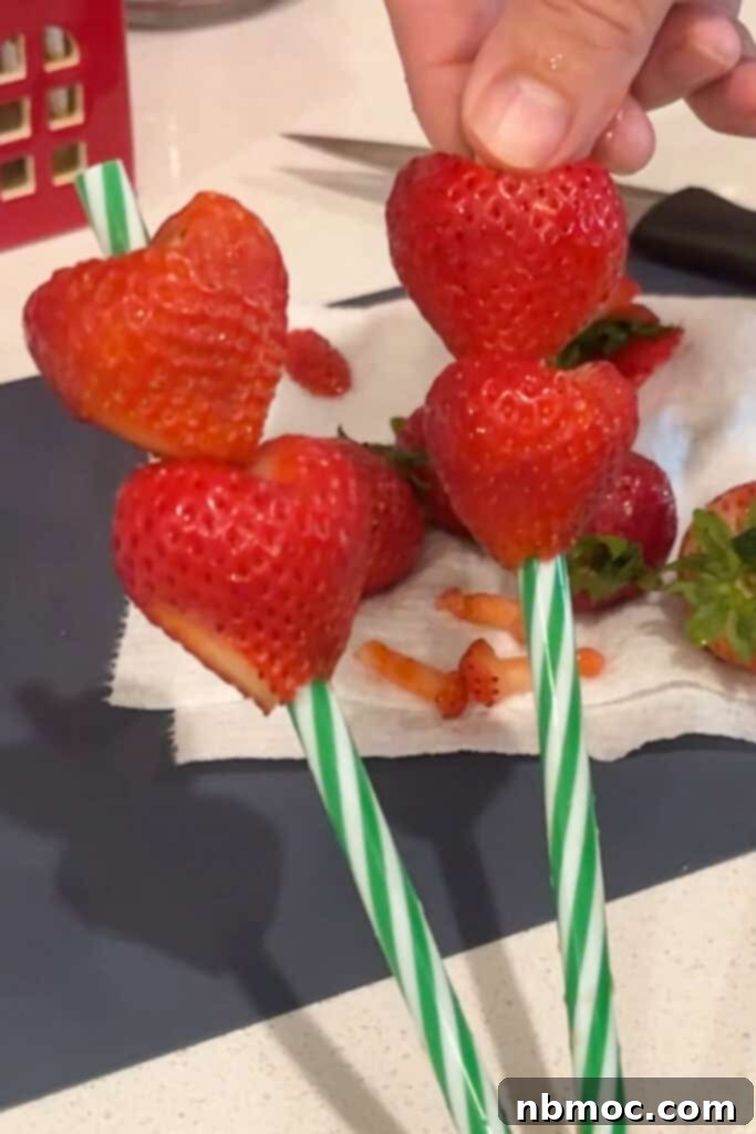 Grinch's Green Punch 3 Strawberries cut into heart shapes and stuck on straws, ready to garnish the Grinch Punch.