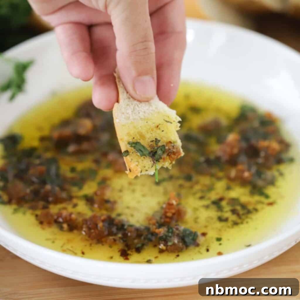 A hand dipping bread into olive oil dip.