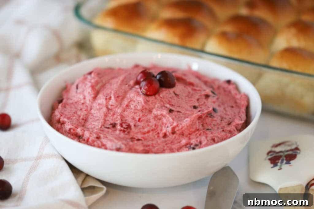 Honeyed Cranberry Cream 4 A inviting bowl of freshly made cranberry butter, rich in color and smooth in texture, positioned with homemade dinner rolls in the background, ready for serving.