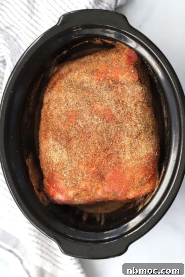 Slow Cooker Pulled Pork Roast ready to cook. picnic roast crock pot, picnic shoulder roast. An unseasoned pork roast sits in a slow cooker.