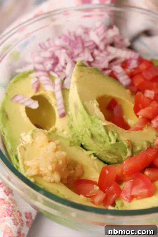 Avocadoes, red onion and tomatoes in a bowl ready to make guacamole. best guacamole recipe. 