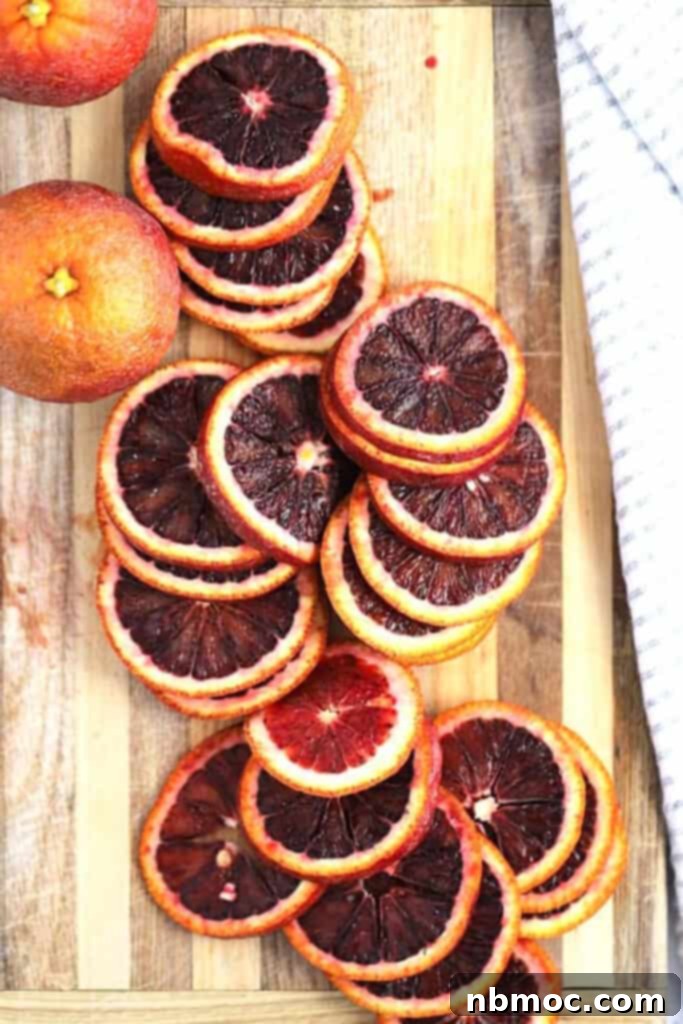 Citrus Gems 3 Fresh blood oranges and lemons on a wooden cutting board, meticulously sliced, ready for the candying process to create homemade candied citrus slices.