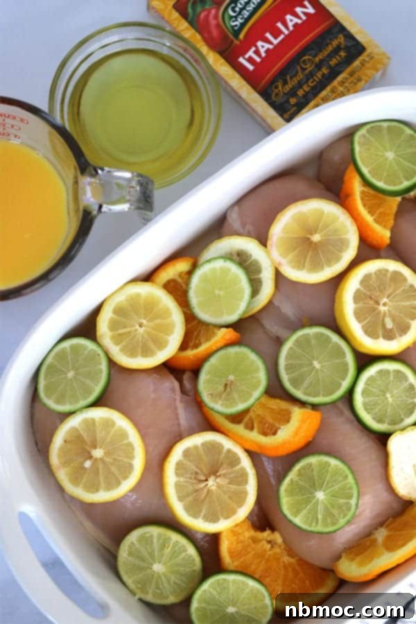 Tender chicken breasts marinating in a vibrant citrus marinade, topped with fresh slices of oranges, lemons, and limes in a baking dish. This zesty orange juice chicken marinade guarantees juicy results.