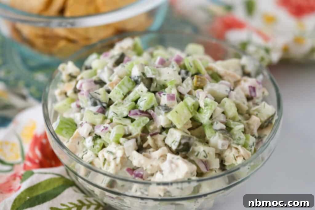 A glass serving bowl full of dill pickle chicken salad. pickles in chicken salad flavor variation. dill chicken salad. 