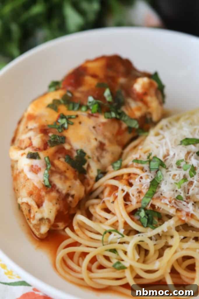 A white serving bowl full of this slow cooker chicken Parmesan crock pot and spaghetti.
