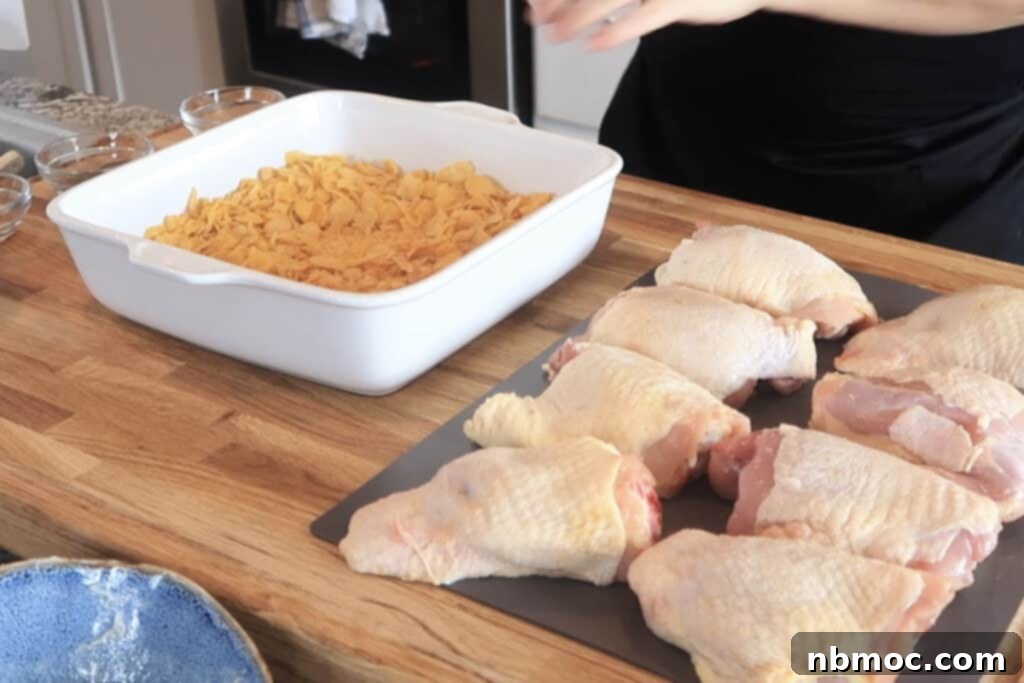 bone in chicken breasts and a white dish of crushed cornflakes.