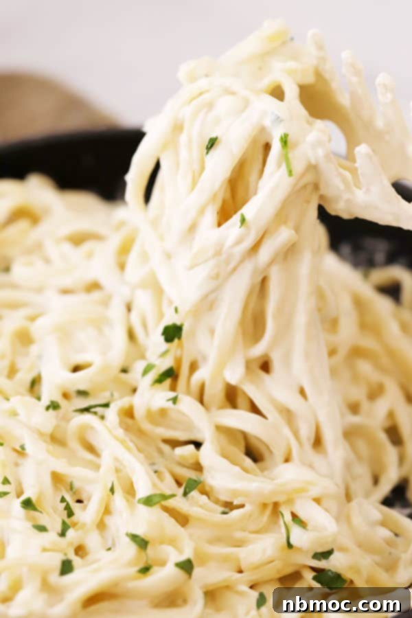 Quick Creamy Alfredo 3 Easy Alfredo Sauce recipe on a bed of fettuccine noodles, garnished with fresh herbs.