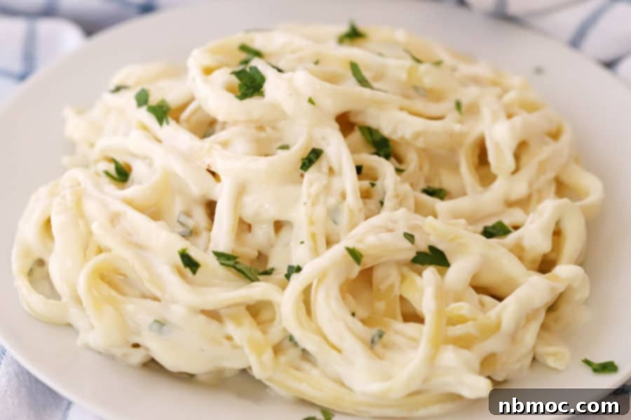 Quick Creamy Alfredo 5 Homemade fettuccine Alfredo served on a white plate, garnished with fresh herbs, ready for a delicious dinner.