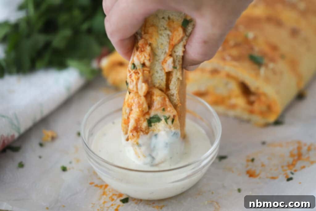 Buffalo Chicken Turnover 3 A hand dipping chicken Stromboli into ranch dressing.