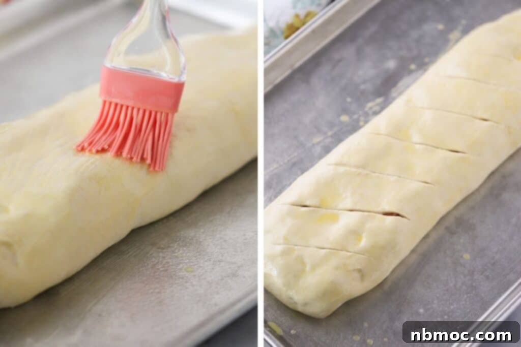 Brushing egg wash over the top of stromboli dough.